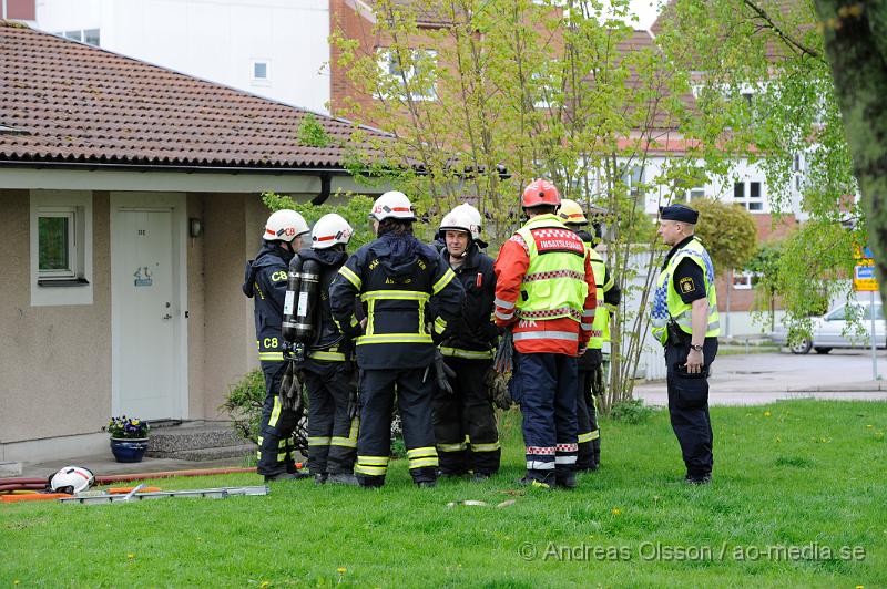 _DSC8268.JPG - Vid 10.40 larmades en större räddningsstyrka med räddningstjänsten från Åstorp, Klippan, Helsingborg samt polis och ambulans till ett radhus på hantverkargatan i Åstorp där man fått in larm om brand i en av lägenheterna. På plats konstaterade räddningstjänsten från åstorp att det var en fullt utvecklad brand i lägenheten men man fick snabbt kontroll över branden men hela lägenheten skadades. Ingen person ska ha kommit till skada men tyvärr avled en hund i branden. Enligt vittne på plats hade man sett en kvinna kasta in något genom fönstret strax innan branden började. Polisen rubricerar händelsen som grov mordbrand.