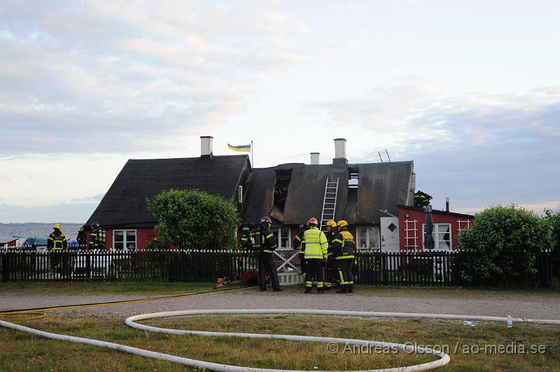 _DSC9456.JPG - Vid 20:20 larmades räddningstjänst, ambulans och polis till Kustgatan i Råå där man hade fått larm om brand i taket på Villa Sjösäker. Väl på plats konstaterade man brand i taket av villan och man skickade in rökdykare och fick såga upp hål i taket för att komma åt branden. Man lyckades rädda villan från totalskada men stora delar av huset blev rökskadat, störst skada blev det i den norra delen av huset. Huset är från 1800 talet och har renoverats i omgångar. Man misstänker att branden startat efter takarbete. Även en person ska ha skadat handen i branden.