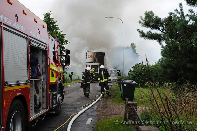 _DSC9674.JPG - Vid 11.10 larmades räddningstjänsten från Klippan och Ljungbyhed samt polis och ambulans till Stackarp strax utanför Klippan där en lastbil kolliderat med en personbil . Lastbilen började strax efter kollisionen brinna och branden spred sig till en mindre byggnad intill samt lite gräs. När räddningstjänsten kom till platsen var lastbilen helt övertänd och totalförstördes precis som byggnaden. En person i personbilen fick följa med ambulansen med oklara skador. Lastbils föraren chockades. Lastbilen ska ha varit lastad med trävaror. Vägen var helt avstängd under räddnings och bärgnings arbetet.