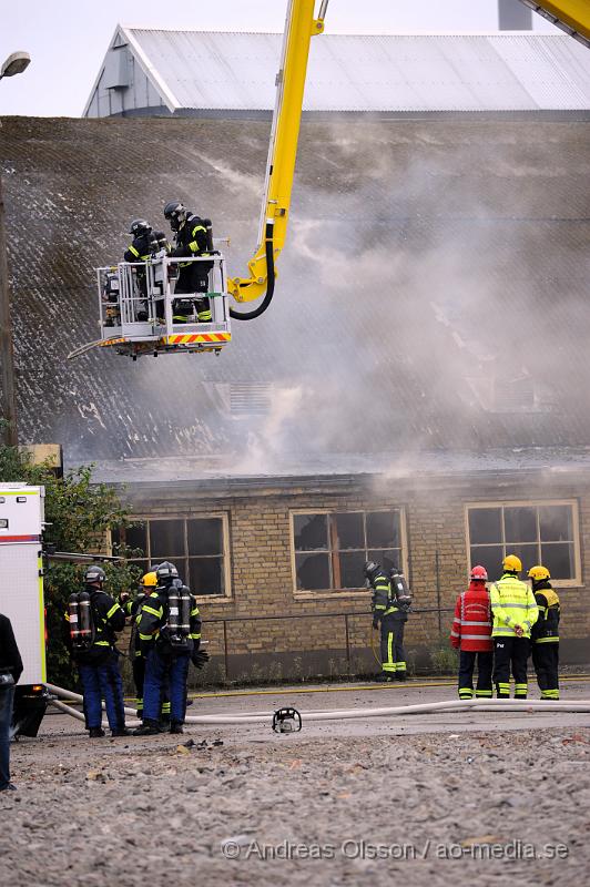 _DSC2315.JPG - Vid 19 tiden larmades en större räddningsstyrka till Skogsgatan i Helsingborg där det kom svart rök från swebus gamla bussgarage. När räddningstjänsten kom till platsen brann det med öppna lågor från taket. Byggnaden är kulturskyddad och det är oklart om räddningstjänsten lyckas rädda byggnaden för det brinner under taket som är gjort av eternitplattor. Strax innan det började brinna i byggnade har vittnen berättat att man sett minst fyra personer lämna området.  Ingen person ska ha kommit till skada.