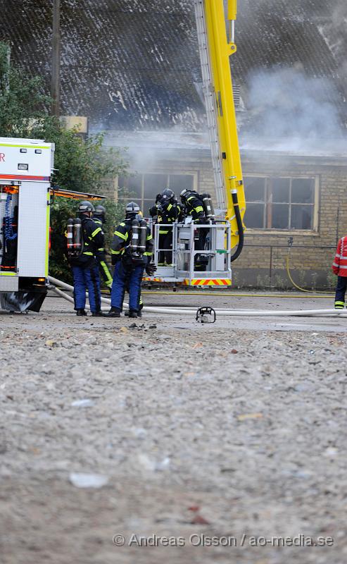 _DSC2317.JPG - Vid 19 tiden larmades en större räddningsstyrka till Skogsgatan i Helsingborg där det kom svart rök från swebus gamla bussgarage. När räddningstjänsten kom till platsen brann det med öppna lågor från taket. Byggnaden är kulturskyddad och det är oklart om räddningstjänsten lyckas rädda byggnaden för det brinner under taket som är gjort av eternitplattor. Strax innan det började brinna i byggnade har vittnen berättat att man sett minst fyra personer lämna området.  Ingen person ska ha kommit till skada.