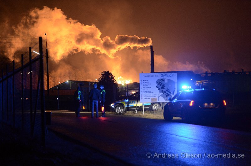 DSC_7895.JPG - Vid 21.40 larmades räddningstjänst, ambulans och polis till Gyllsjö trä i Stidsvig där man hade en fullt utvecklad brand i ett pall lager med ungefär 10 000 trä pallar. Lagret var helt övertänt när räddningstjänsten kom fram till platsen och man inrikta sig direkt på att skydda omkring liggande byggnader. Bland annat produktionslokalen som ligger ungefär 20 meter från pall lagret. Den kraftiga strålnings värmen från branden gjorde att det började brinna lite i fasaden på produktionslokalen men man lyckades begränsa branden och skydda byggnaden. Vid tre tiden på natten fick man en brand uppe i taket på produktionslokalen och man fick sätta in fler resurser, men kallade in en hävare och skickade upp folk på taket för att begränsa branden och kontrollera så den inte kunde sprida sig. Det arbetet gav också snabbt resultat och skadorna blev bregränsade. Ingen person har kommit till skada men lager byggnaden är helt nedbränd och produktionslokalen har fått skador i ena fasaden. Räddningstjänsten hade flera stationer på plats under kvällen/natten, Klippan, Åstorp, Ljungbyhed; Örkelljunga, Ängelholm, Helsingborg.